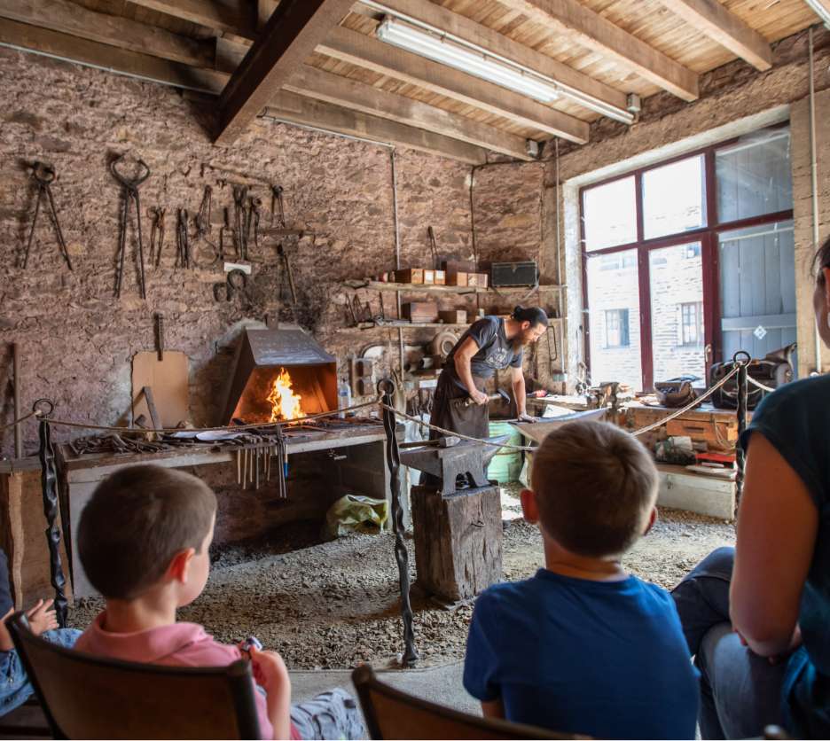 visiteurs musée observent forgeron