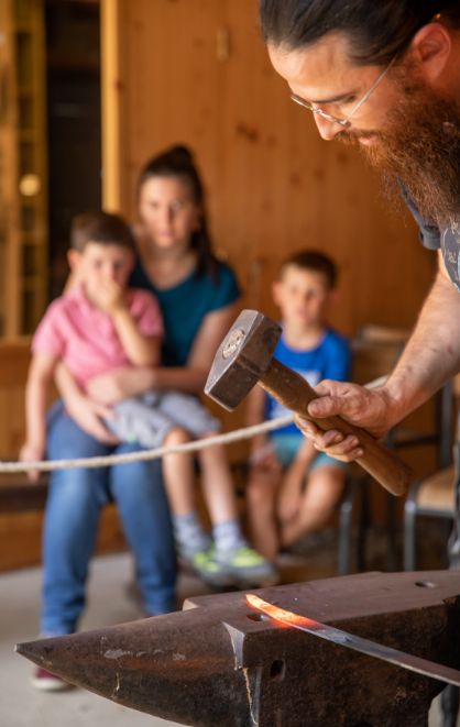 famille observe forgeron façonner acier