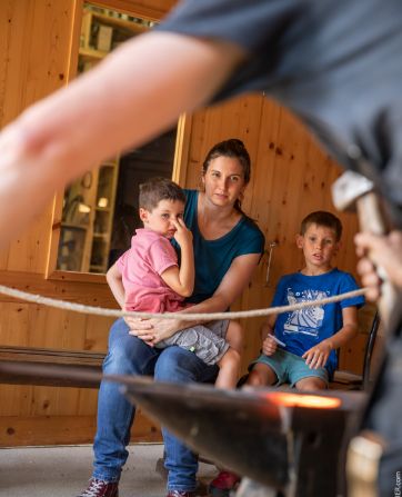 famille observe forgeron travailler fer